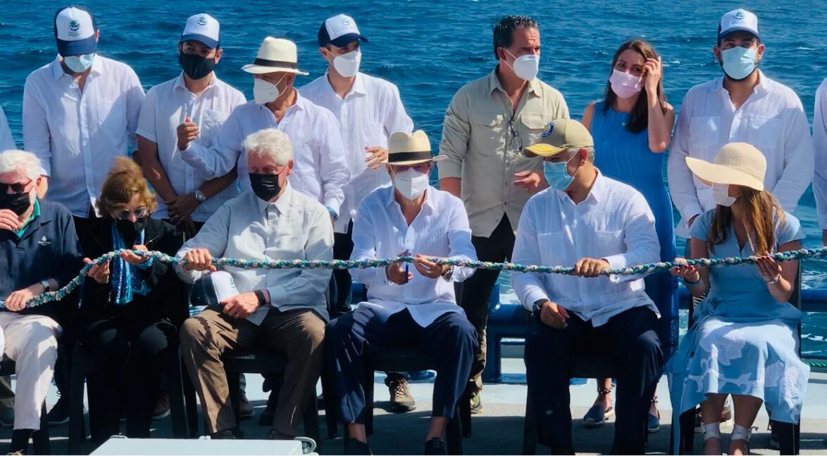 Cutting a ribbon made with recyclable material that was collected in coastal cleanups