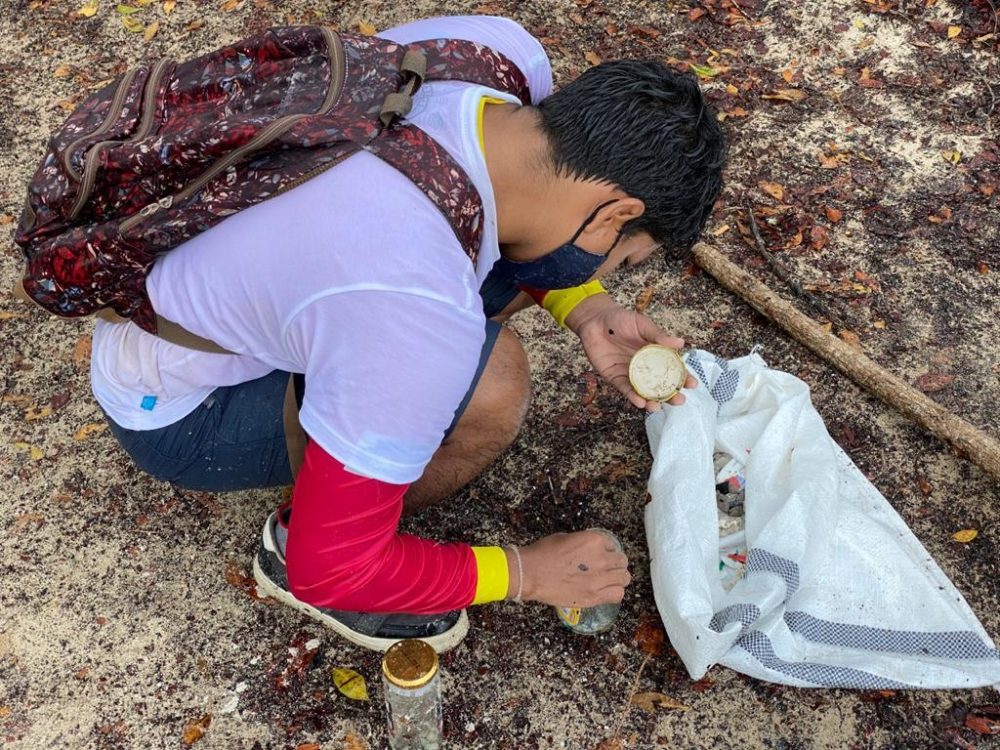 A man wearing a mask is learning how to sample microplastics on a beach in Galapagos